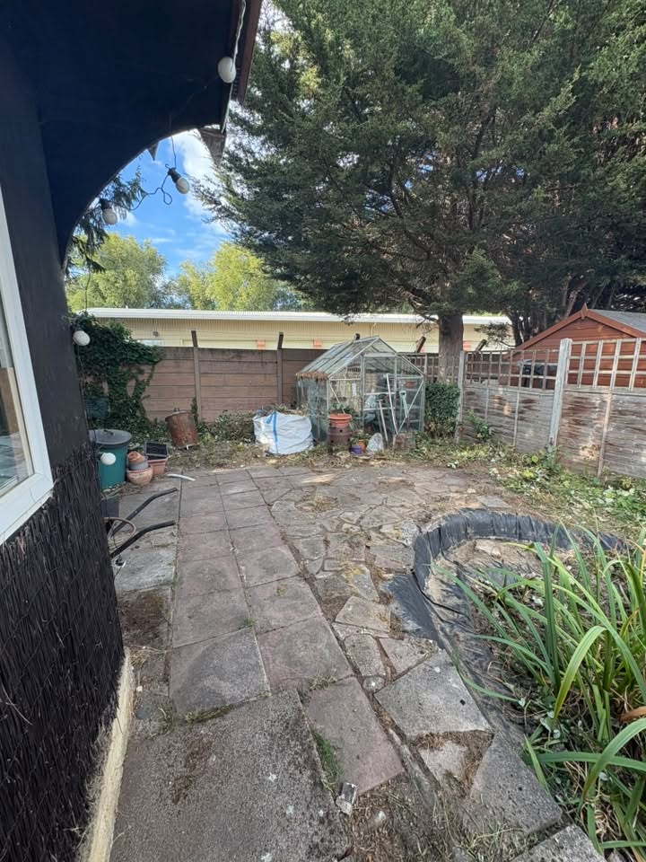 A garden tidy-up, clearing away overgrown plants and unwanted growth, revealing the stone patio hidden underneath.